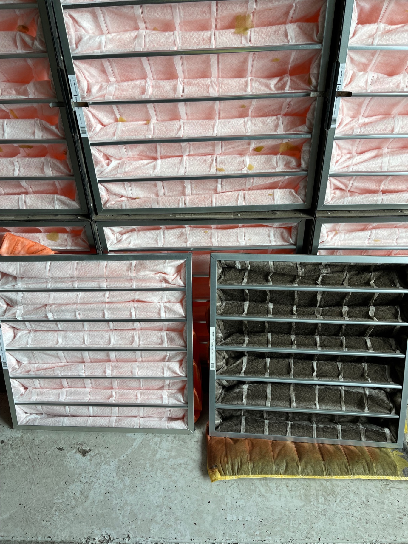 Close-up of commercial air filters showing new pink filters next to a used carbon filter